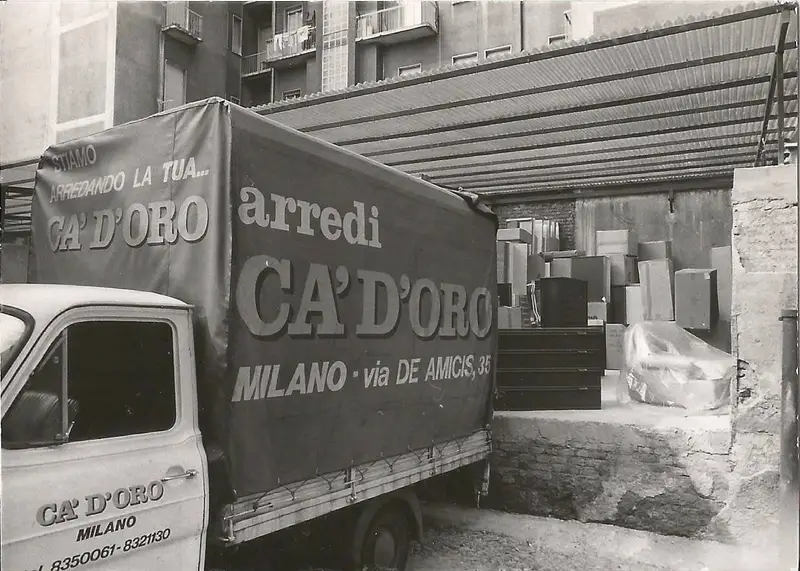 Un furgone telonato con la scritta «Ca’ d’Oro arredi, Milano, via De Amicis» fra le casse dei mobili