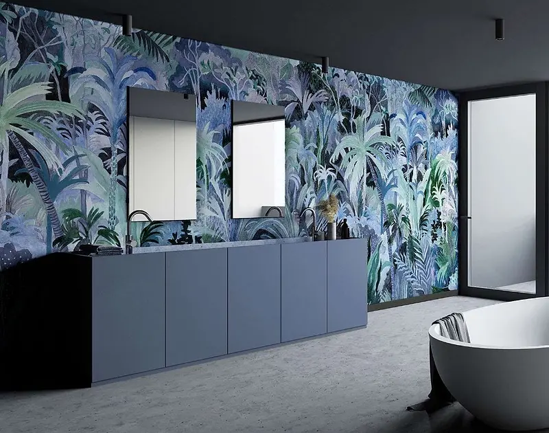 Una parete rivestita di carta da parati con foglie e fiori blu, dietro un mobile basso