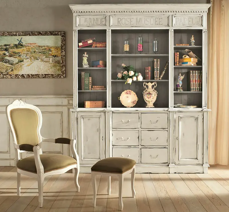 Un salotto classico con poltrona intagliata, credenza chiara e quadri alle pareti
