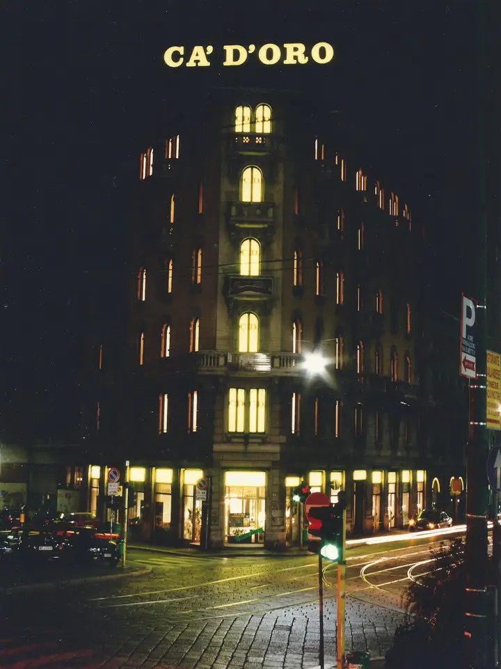 Il palazzo di Ca’ d’Oro di notte: tutte le finestre accese, l’insegna sul tetto, le vetrine del pianterreno illuminate sulla piazza